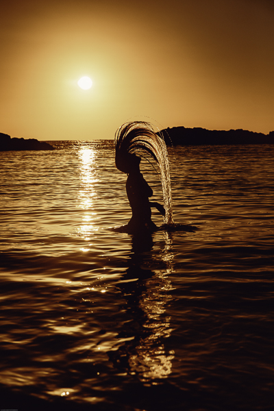 Sunset photo in hawaii with woman doing a hair flip
