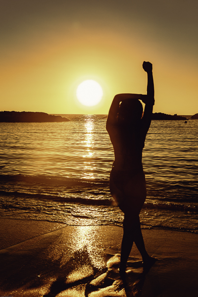 Hawaii sunset beach shoot with woman standing facing the sun